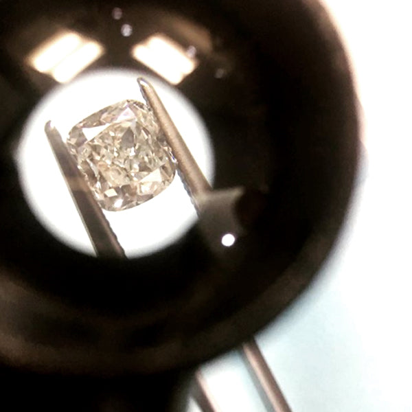 Tweezers holding a glistening diamond in the light.