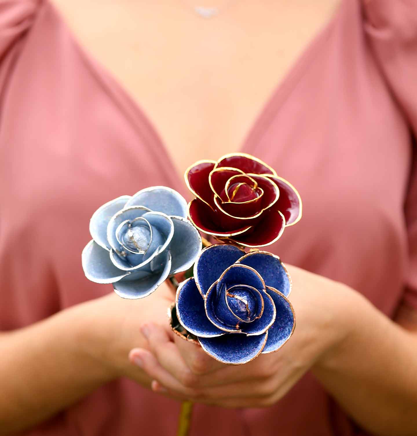 A girl holding a bouquet with a Mystic Blue Platinum Rose, Red Wine 24 Karat Gold Dipped Rose, and Periwinkle Rose Gold Dipped Rose. 